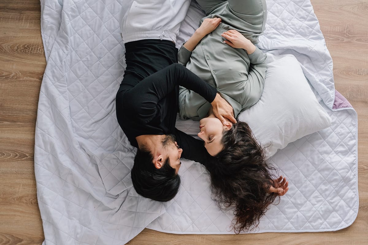 Photo of loving couple laying down on a bed